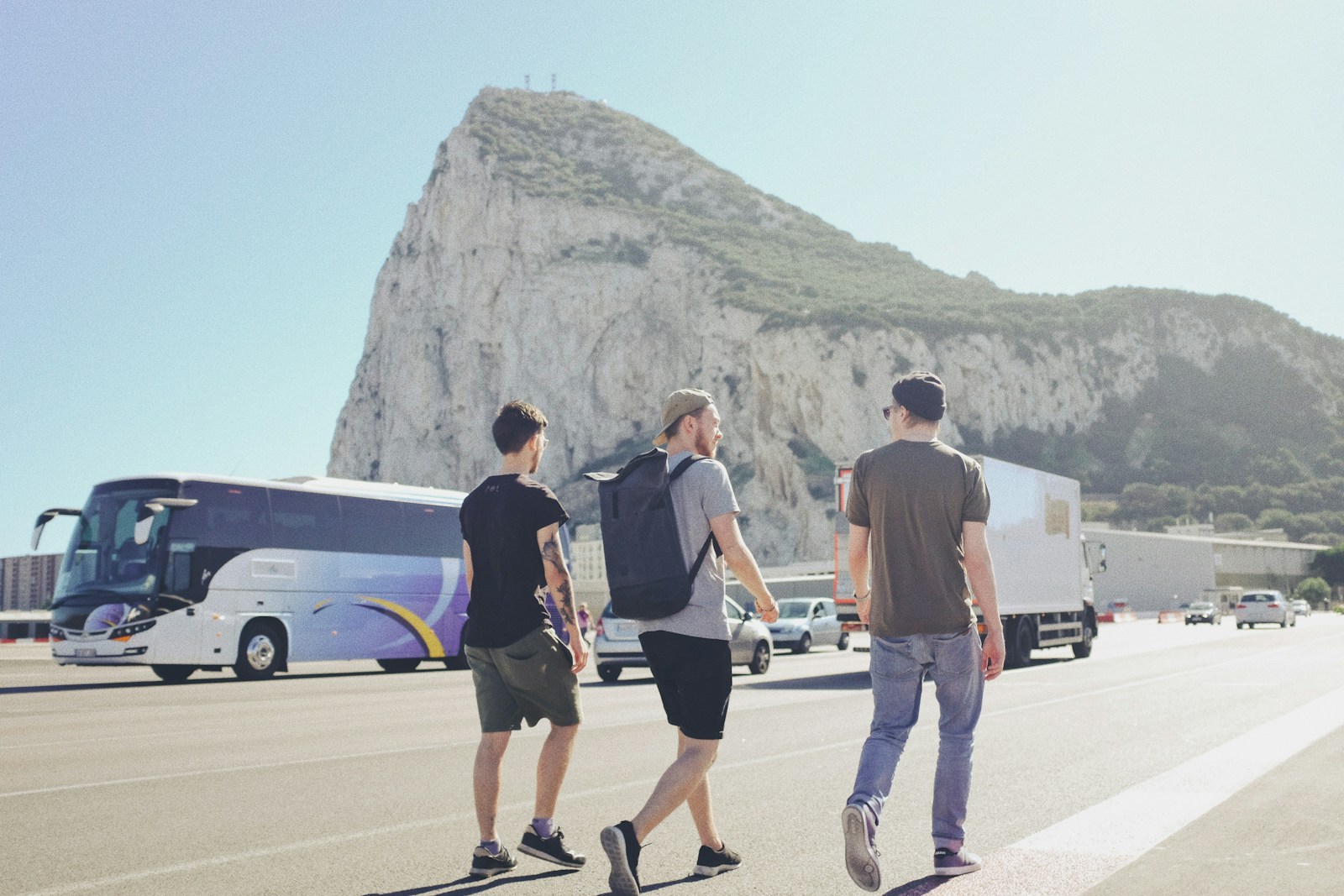 three men walking on street near vehicles during daytime